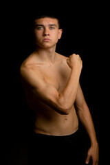 Naklejka premium Nineteen year old teen boy flexing his arm muscles