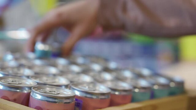 The female hand of a white girl takes a metal can. Buying soda in a supermarket store