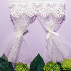 Lace curtains and fresh green leaves, creative natural concept against pastel purple background. Open window and garden idea. 