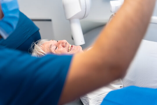 Dental clinic, elderly woman sitting smiling at the dentist waiting for denture check-up