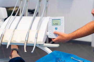 Dental clinic, hands of a dentist lowering the chair to the client before the operation