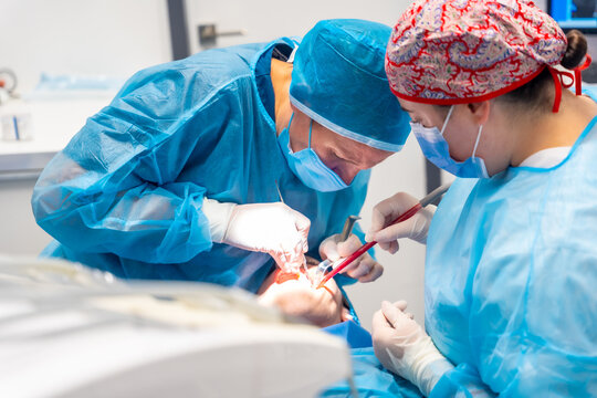 Dental Clinic. Female Dentists In Blue Scrubs Performing A Complicated Operation On A Female Patient, Flat Lay Photo