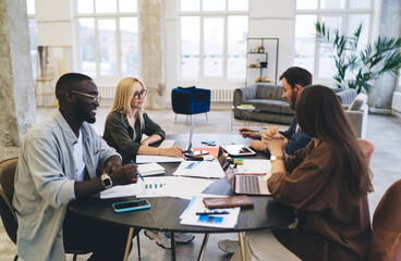 Diverse coworkers discussing project in creative workspace