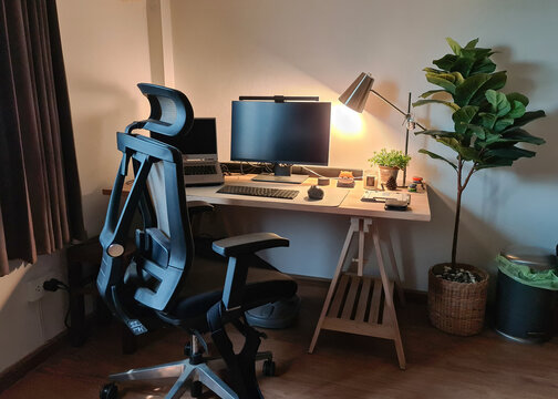 Working corner with monitor, laptop, wooden desk, ergonomic chair and decorate object