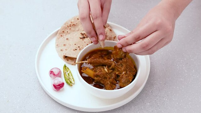 A person eating home-cooked mutton gravy or mutton curry  with roti and onion salad in 4k resolution