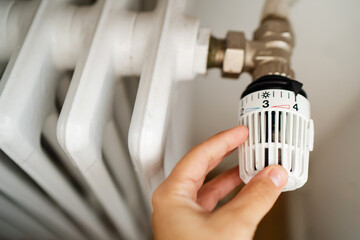 Rising heating costs in a crisis: people adjust the temperature in the house using a heating...