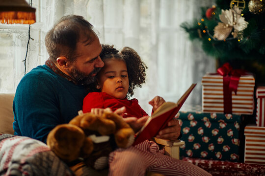 Father and his little daughter reading book - Powered by Adobe
