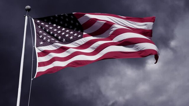 Wind blowing American flag composited over time-lapse of stormy clouds 