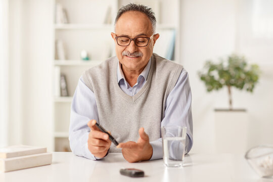 Mature man sitting at home and checking blood sugar level