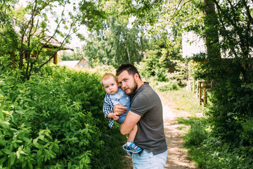 Naklejka na ściany i meble Dad and little son spend time together in the summer outdoors, have fun