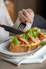 Sandwich, bruschetta with shrimp, fresh salad and sweet and sour sauce in a restaurant serving. The girl cuts a shrimp sandwich.