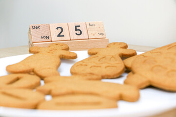 Christmas Day concept, 25th December displayed via wooden blocks in focus, in the foreground out of focus are a plate of Christmas gingerbread biscuit treats