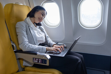 Young Asian business woman talking on smartphone, businesswoman working while flying at plane, Young woman using the internet at airplane, Air travel, long flight.