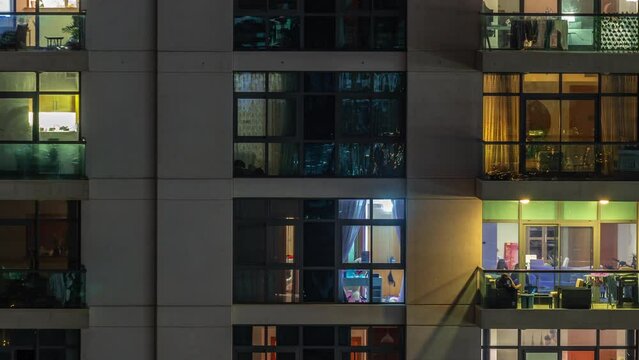 Windows of apartment building at night timelapse, the light from illuminated rooms of houses. Relaxing zone on balconies. Urban landscape of the skyscrapers