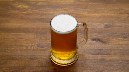 A large mug of light tasty cold beer on a wooden table, close-up, rustic style