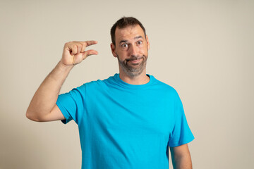 I need some more, please give me. Bearded man showing small gesture with skeptical smile, showing...