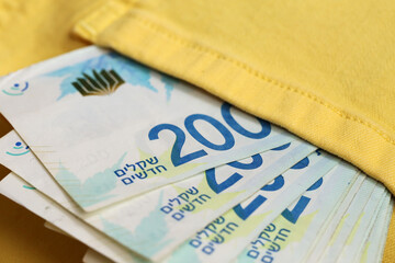 Obraz premium in the pocket of yellow jeans is a pack of shekels in bills of two hundred