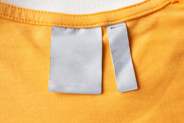 Blank white laundry care clothes label on yellow fabric texture background