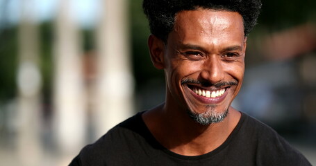Black man laughing out loud reacting to joke. African person standing outside in the sunlight