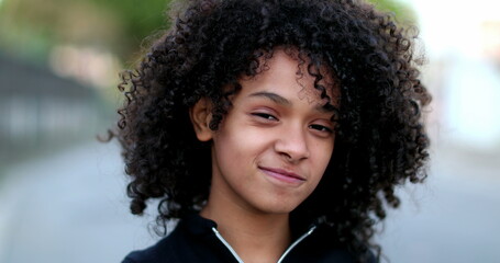 Black preteen girl smiling portrait. Brazilian mixed race child with curly hair face