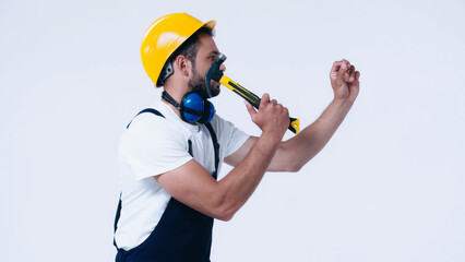 side view of handyman in hardhat working with hammer isolated on white.