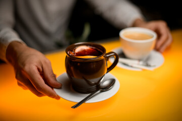 selective focus on male hand holding saucer with cup of tea