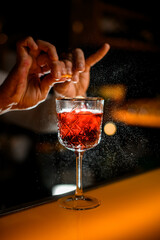 selective focus on glass with alcoholic drink on which the bartender splashes from citrus