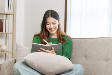 Happy young attractive smiling asian woman enjoying relax time at apartment.