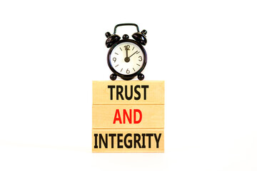 Trust and integrity symbol. Concept words Trust and integrity on wooden blocks. Black alarm clock. Beautiful white background. Business, psychological and trust and integrity concept. Copy space.