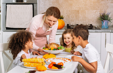 Joyful children at a festive Thanksgiving dinner. Serving a prepared festive dish on the table.