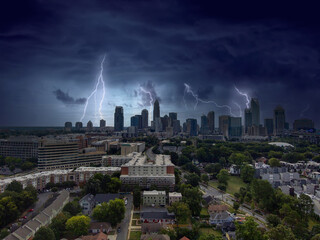 an aerial shot of the skyscrapers and office buildings in the city skyline with lush green trees and with powerful storm clouds and lightning at Frazier Park in Charlotte North Carolina USA © Marcus Jones