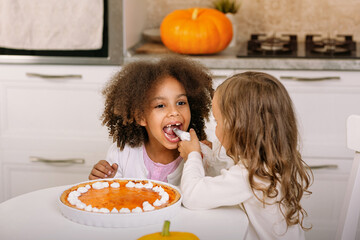 Children decorate pumpkin pie with cream and fool around. Preparations for Thanksgiving
