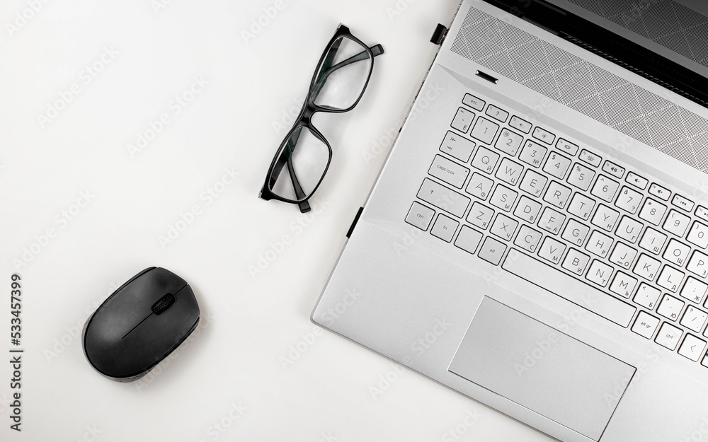 Aufkleber A laptop with glasses and computer mouse are on a white table. Top view with copy space