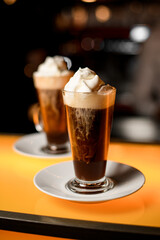 selective focus of latte glass with dark coffee drink garnished with whipped cream