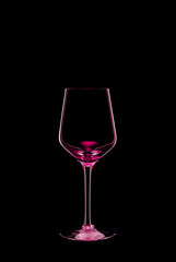 Empty wine glass backlit with bright pink light and isolated on black background. Beverage glassware concept. Copy space.