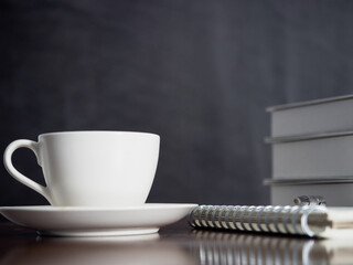 Close up coffee cup with notebook and pen on wood table dark background