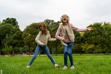 Fototapeta premium Adorable small girls performing freestyle dance together in autumn park