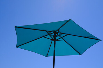 Blue parasol on the beach in a sunny day of summer. Sun protection. Travel and vacations concept./=