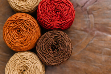 Bright autumn shades of knitted yarn. Coils of thread on a wooden table with space for text. Cozy knitting