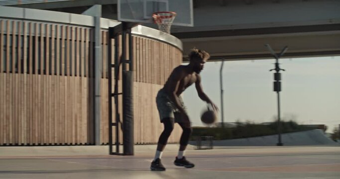 Black basketball player doing tricks near hoop