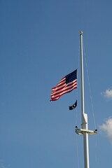 American flag and Prisoner of War flag wave near top of tall flag pole on Lexington Green in...
