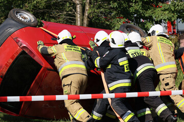 Akcja straży pożarnej podczas wypadku samochodowego. Ratowanie rannego kierowcy.. Ćwiczenia straży pożarnej.  - obrazy, fototapety, plakaty