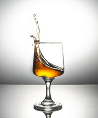 Apple juice splash going out of glass with wheel in the bottom