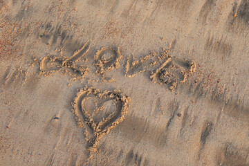 writing message LOVE on the  sand beach
