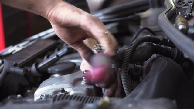 young auto mechanic repairs a car engine. spark plug replacement.