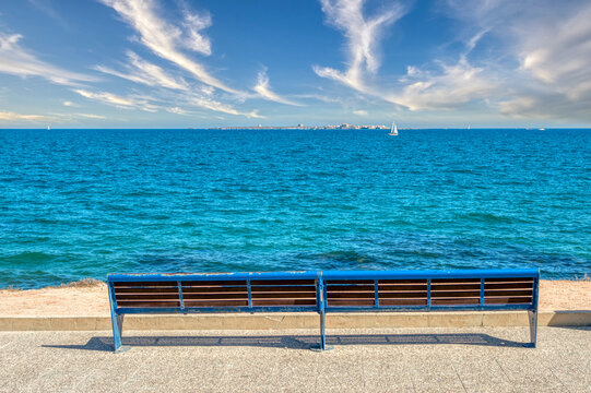 METAL BENCH PAINTED BLUE AND IN THE BACKGROUND THE ISLAND OF TABARCA, ALICANTE, SPAIN