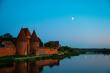 Naklejka na ściany i meble Marienburg castle the largest medieval brick castle in the world in the city of Malbork evening view at night
