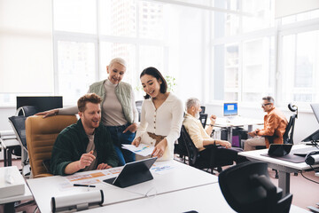 Group of diverse colleagues discussing project together at workplace