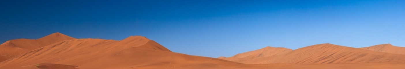 Fototapeta na wymiar wide panorama of red dunes with blue sky at sossuvlei national park in Namibia, stunning wallpaper