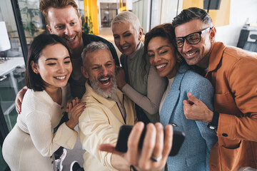 Fototapeta premium Cheerful multiethnic friends taking selfie while hugging together